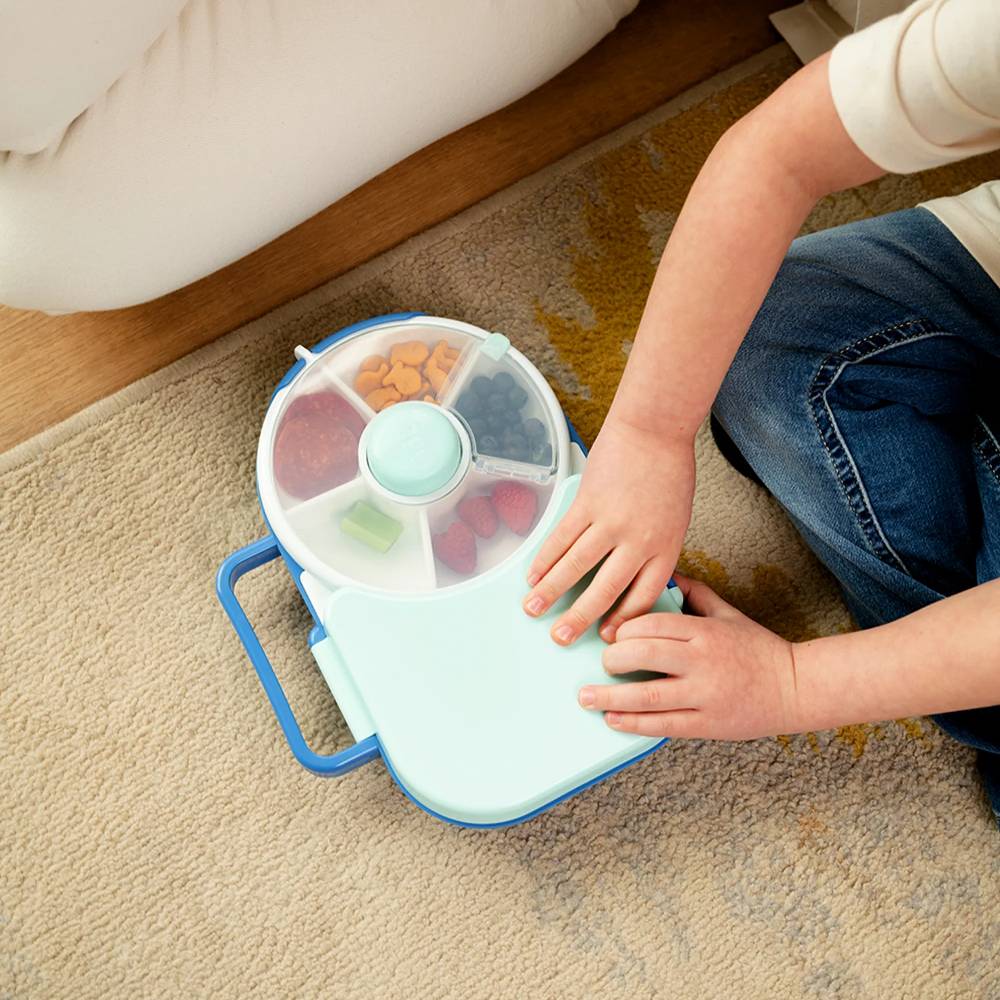 Child using blue Gobe lunchbox against floor.
