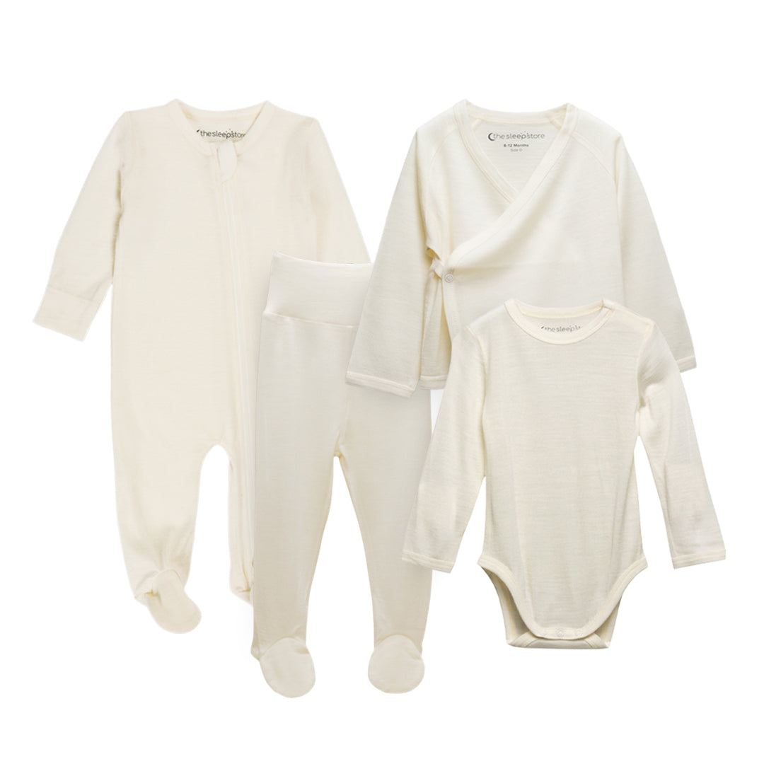 A four-piece baby clothing set in a soft cream/off-white jersey merino fabric, including a long-sleeve footed sleeper, a wrap-style cardigan, and a long-sleeve bodysuit, laid out on a white background.