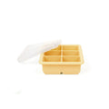 A six-compartment silicone ice cube tray in a warm pale yellow color, shown with its translucent white plastic lid propped open on a clean white background.