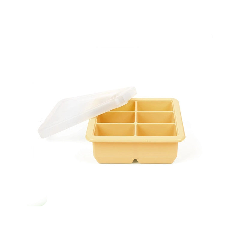A six-compartment silicone ice cube tray in a warm pale yellow color, shown with its translucent white plastic lid propped open on a clean white background.