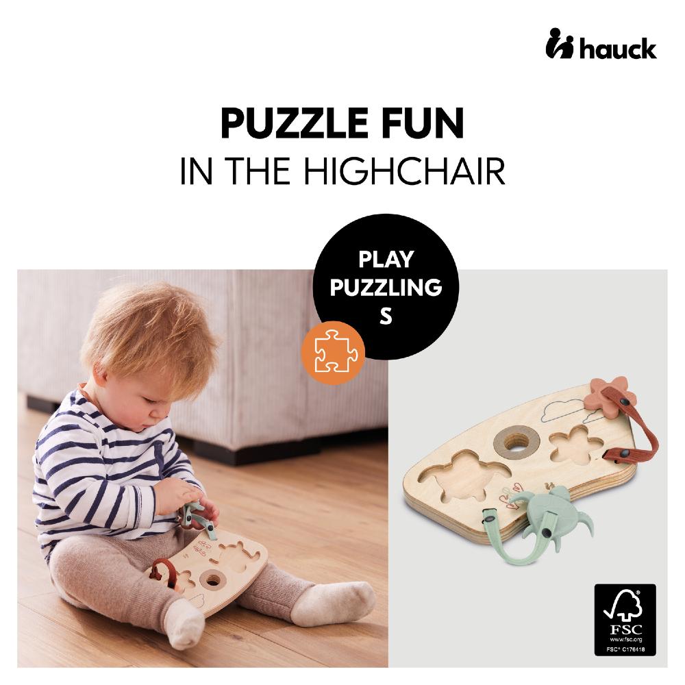 Child playing with a wooden puzzle toy in a highchair, with 'hauck' branding.