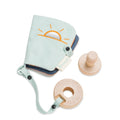 Light blue teething ring and book with sun design and wooden elements on a white background