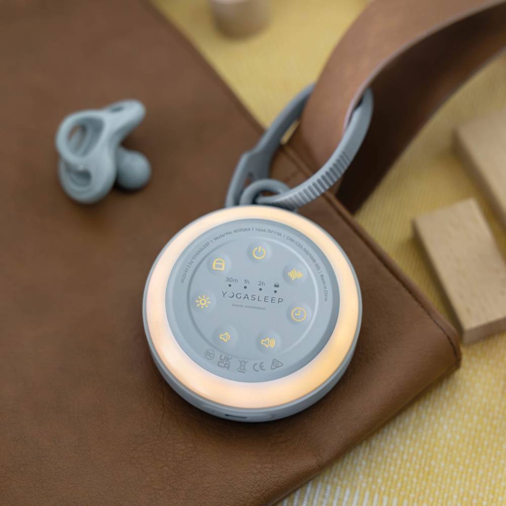 Round white noise machine with pacifier on a brown surface