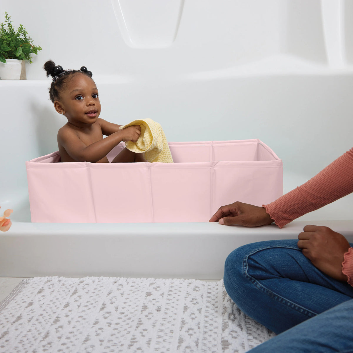 A young child in a Tuckaway Travel Tub - Pink.