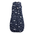 A navy blue baby sleep sack with a white whale and starfish pattern, featuring a front zipper and a small fabric brand tag near the neckline.