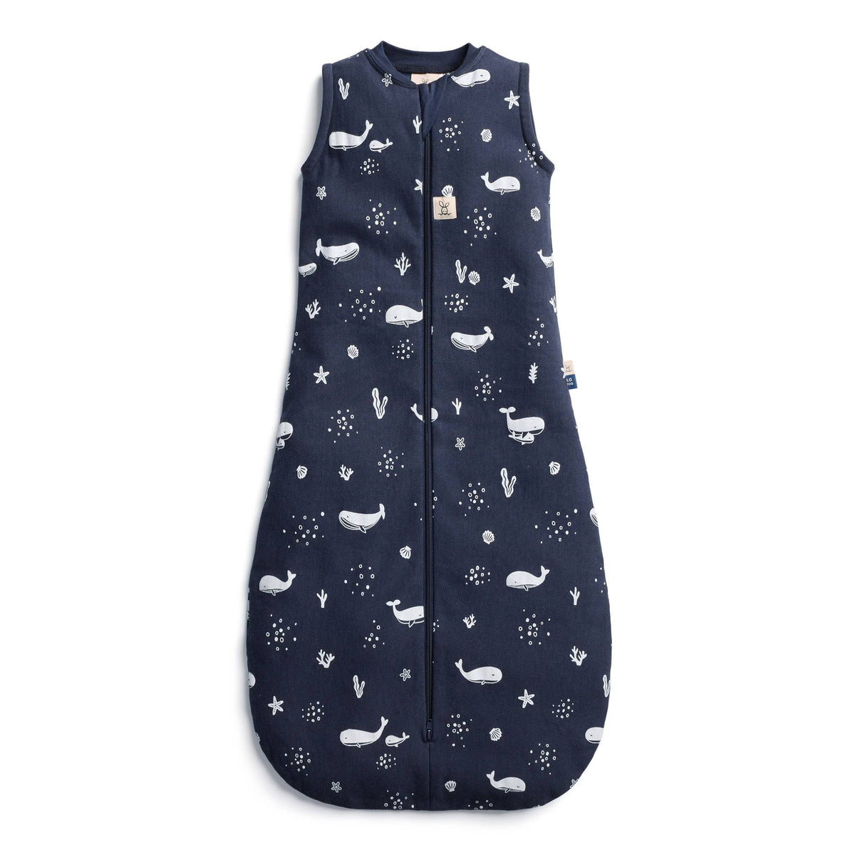 A navy blue baby sleep sack with a white whale and starfish pattern, featuring a front zipper and a small fabric brand tag near the neckline.