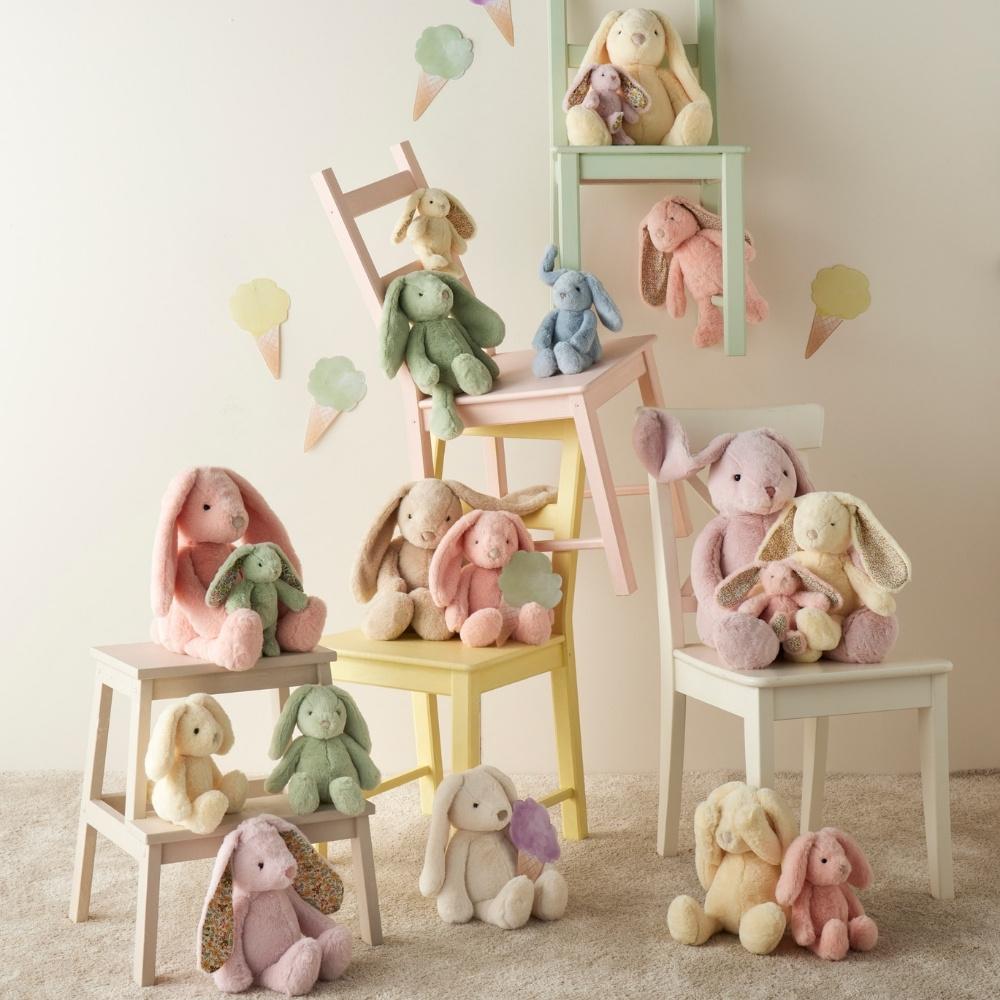 Pastel-colored stuffed animals on small chairs against a light background