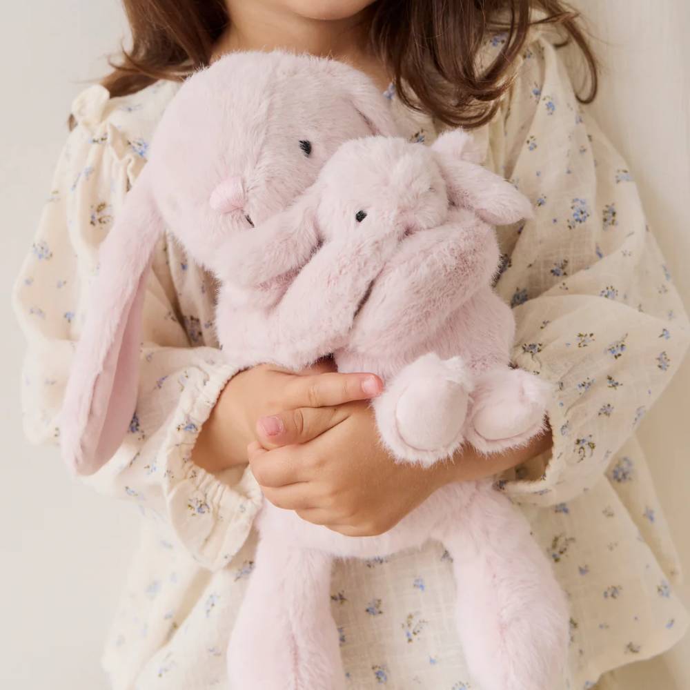 Child holding Jamie Kay pink bunny soft toy.