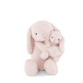Two pink soft toy bunnies hugging on a white background. 