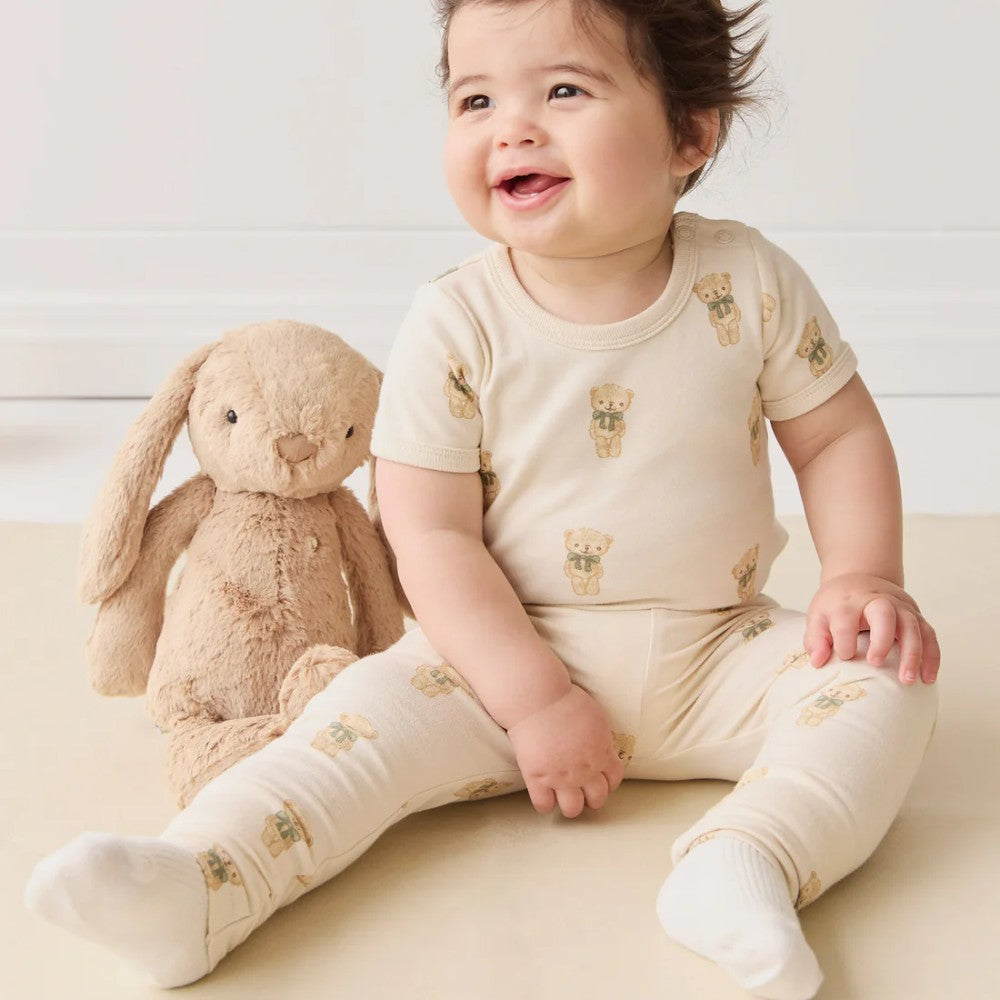 Baby sitting on floor with brown Jamie Kay bunny soft toy.