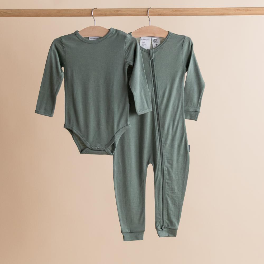 Merino baby onesie with long sleeves and a zipper on a beige background