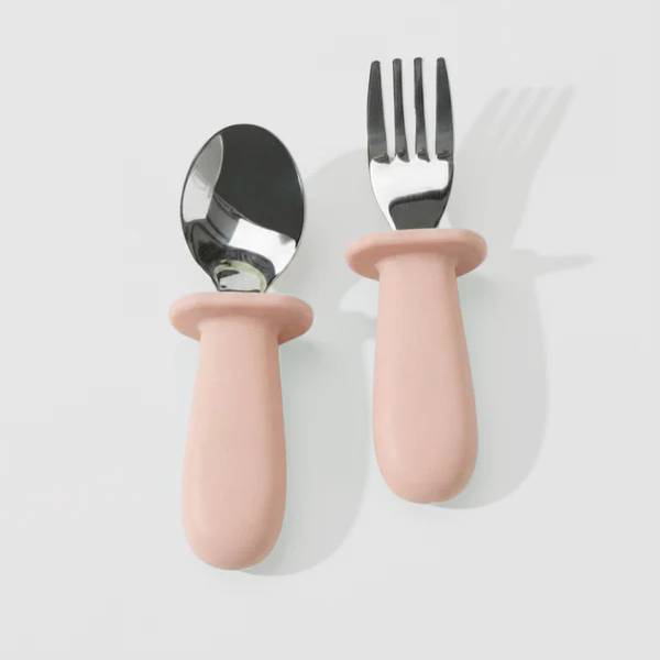 Pink Litill Lapsi fork and spoon against white background.