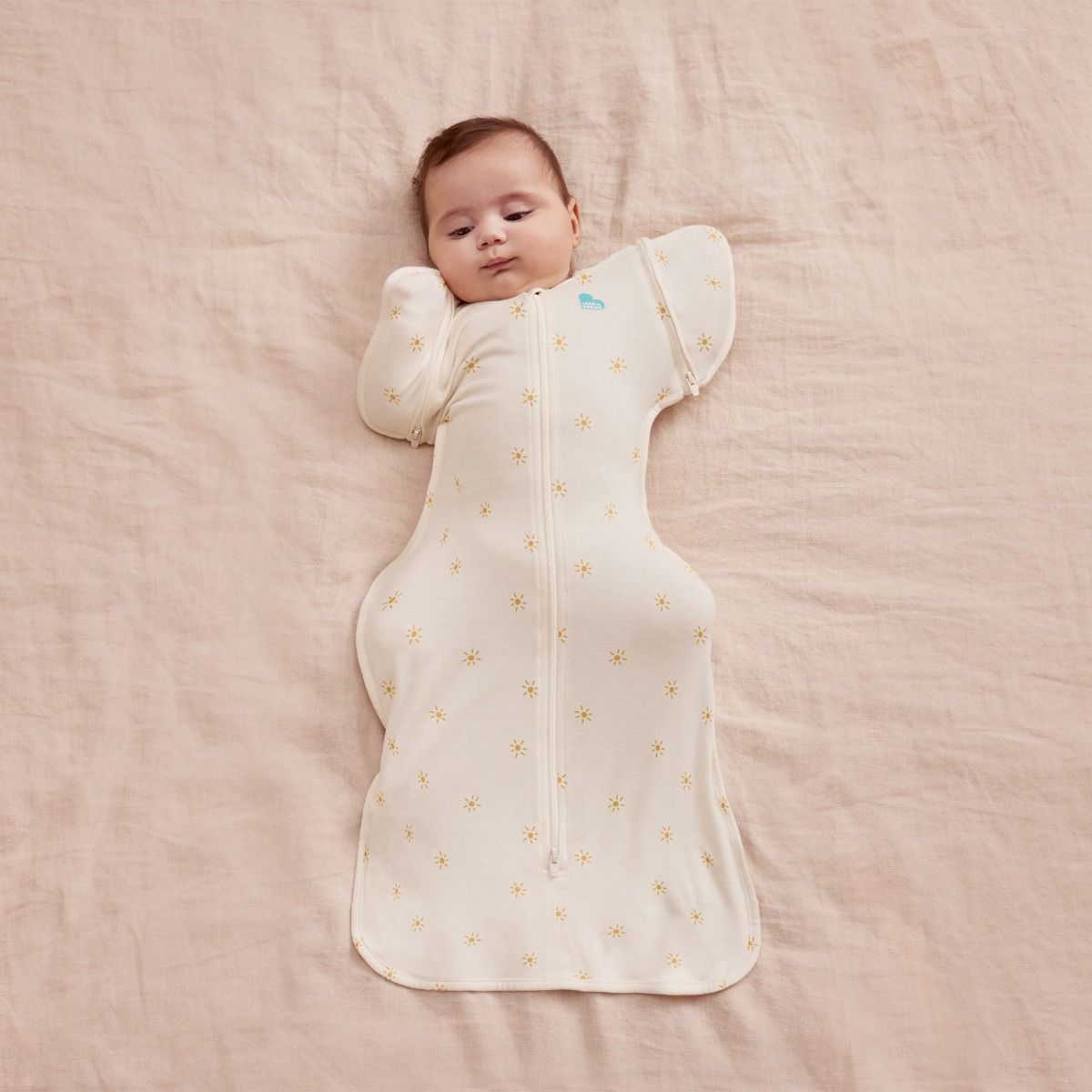 A baby lying down wearing 0.2 tog Swaddle Up Transition Bag Bamboo - Sunny Gold.