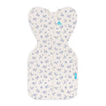 A baby sleep sack with an off-white background and a delicate blue floral pattern, featuring a front zipper and a small blue brand tag.