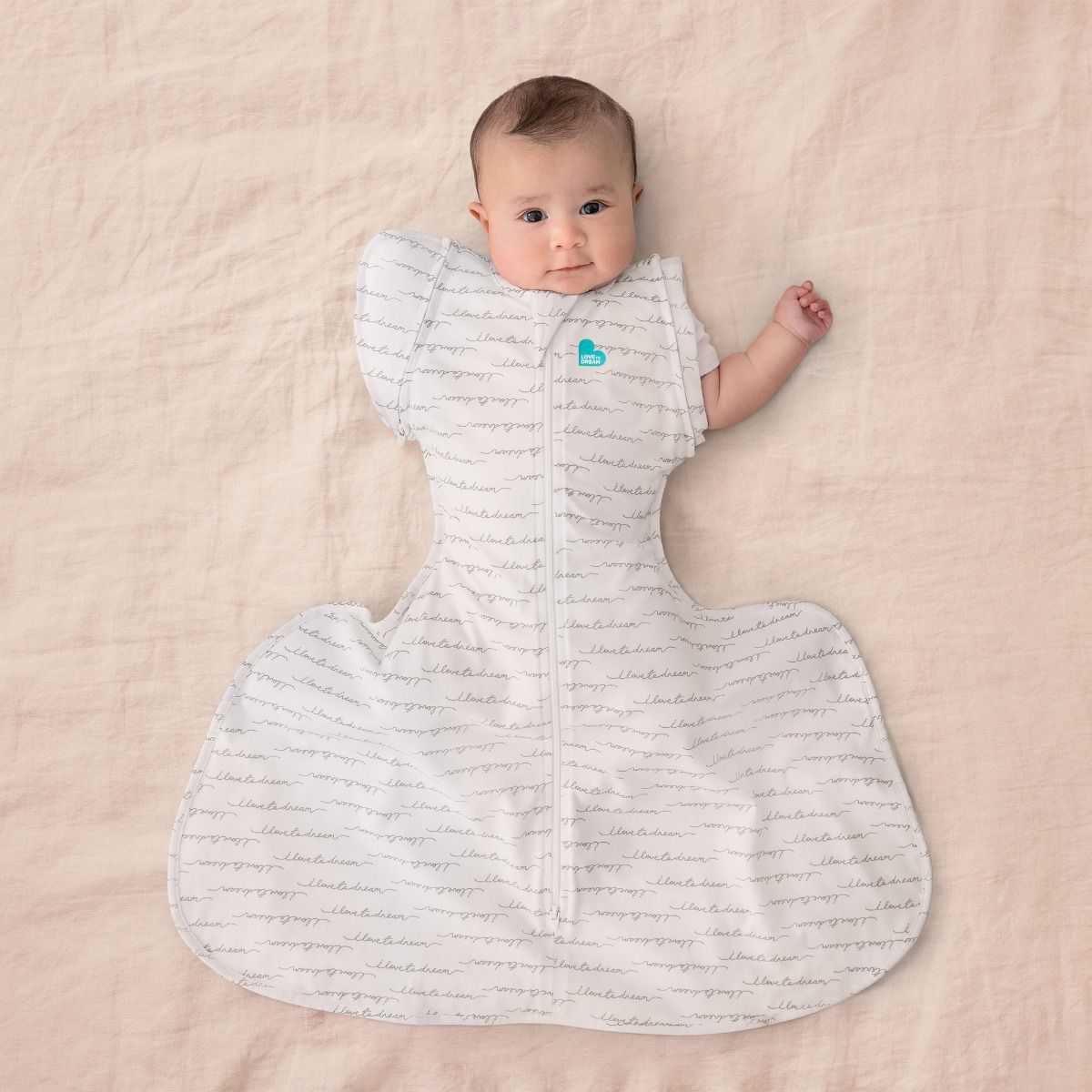 A baby lying down wearing a Swaddle Up Hip Harness Transition Bag - Dreamer. 
