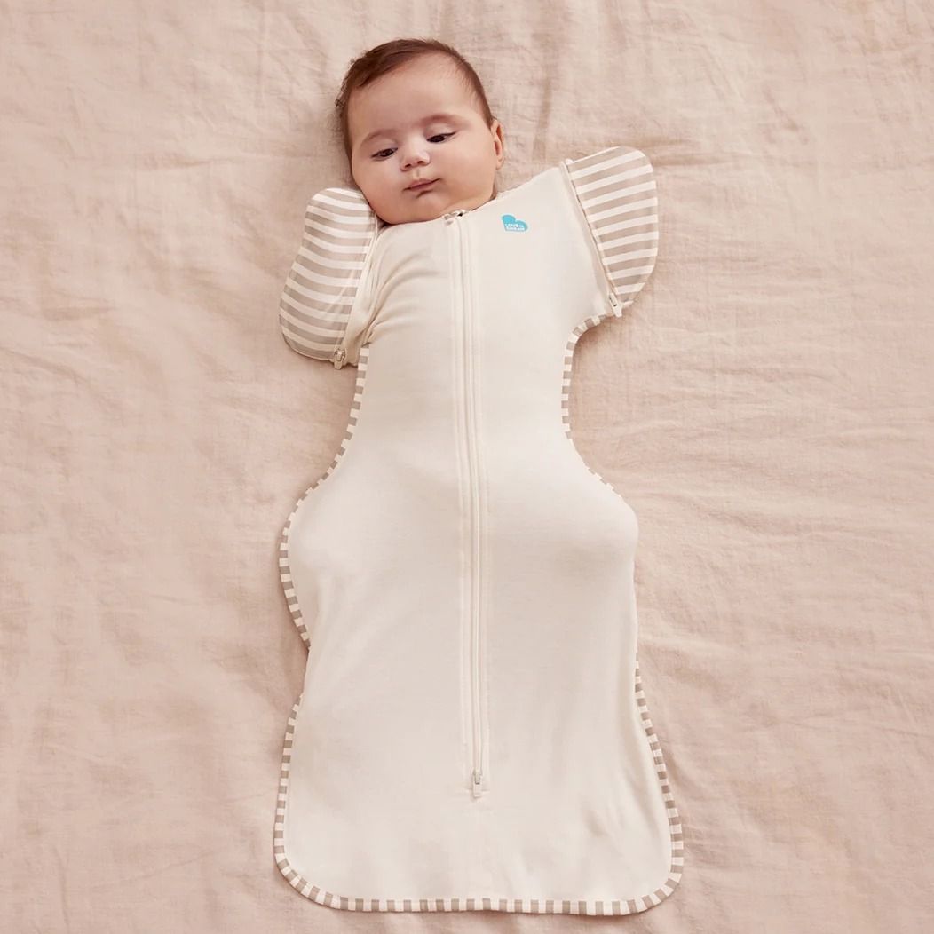 A baby lying down wearing a 1.0 tog Swaddle Up Transition Bag Organic - Cream.