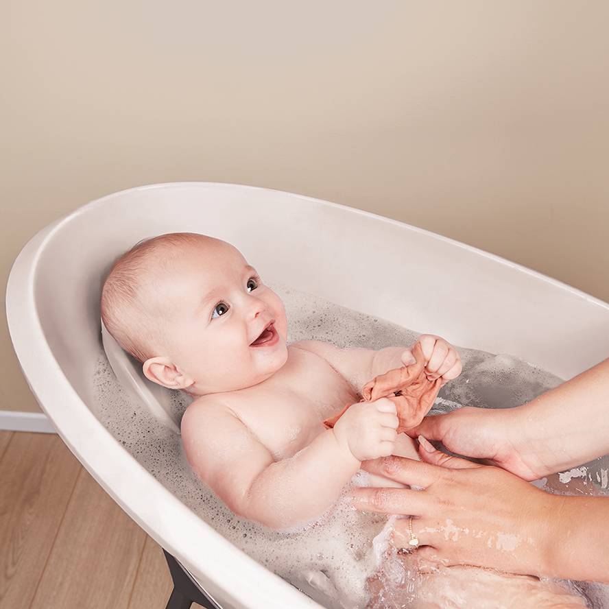 Smiling baby in a LUMA Baby Bath with Bath Support Insert. 