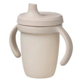 Beige sippy cup with handles and a lid on a white background