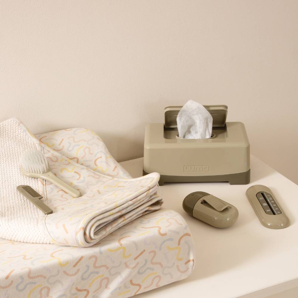Olive Green LUMA Wipes Box on a dressing station with other LUMA baby care items.