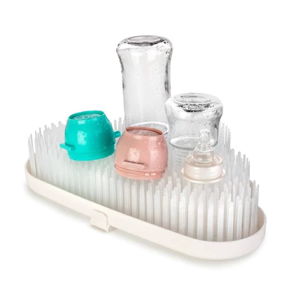 Dish drying rack with various cups and baby bottles on a white background