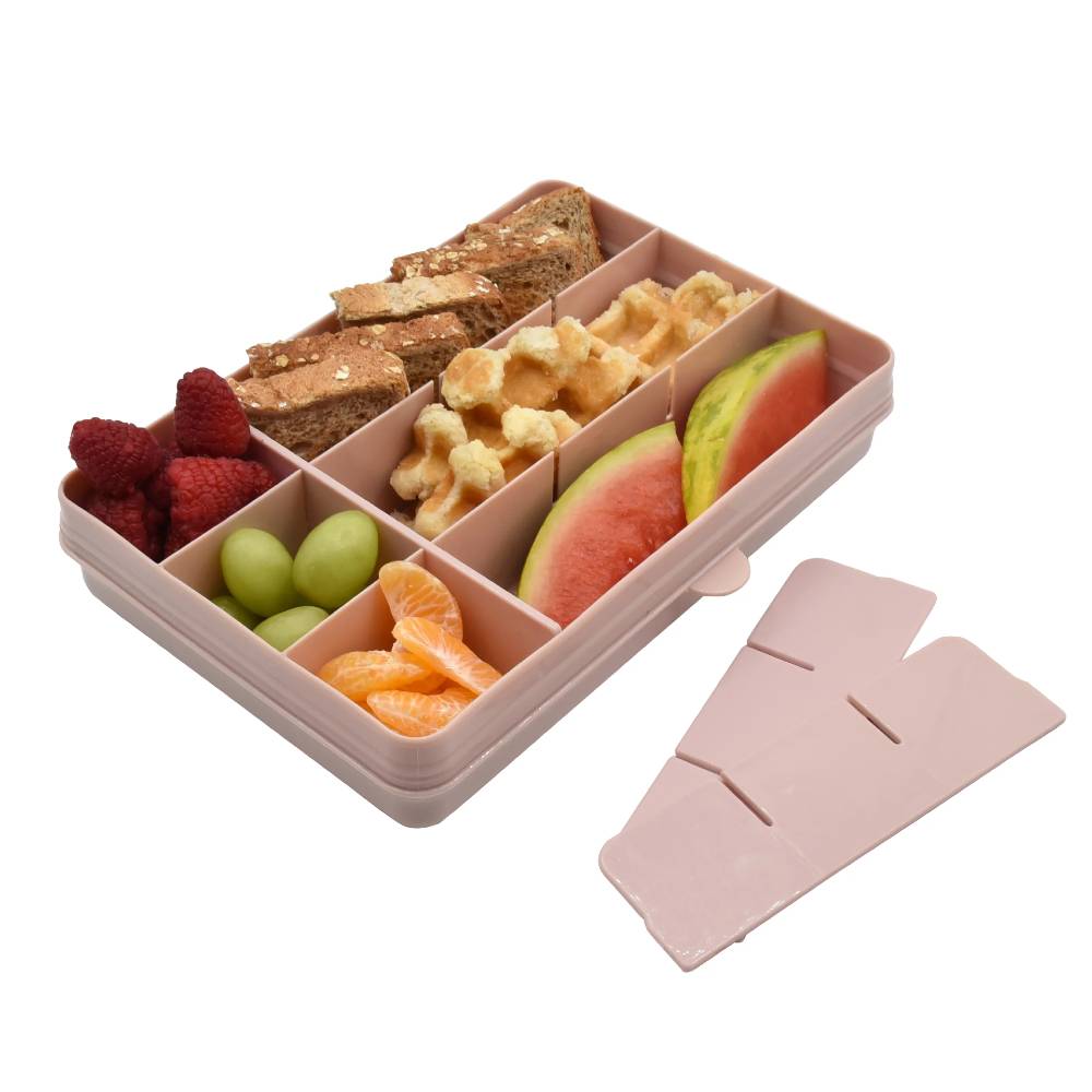 Pink bento box with compartments filled with snacks and fruits on a white background
