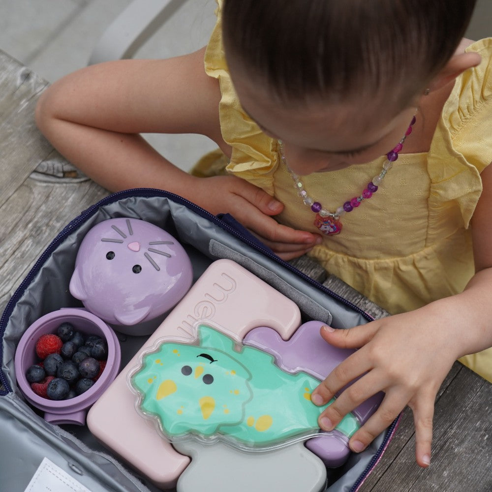 Child playing with a set of colorful silicone food containers on a wooden surface.