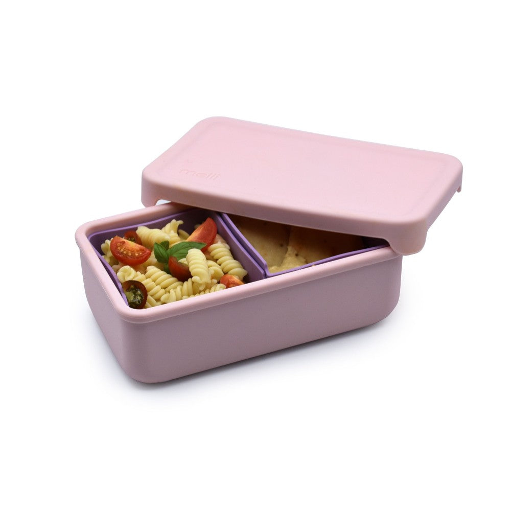 Pink bento box with compartments containing food on a white background