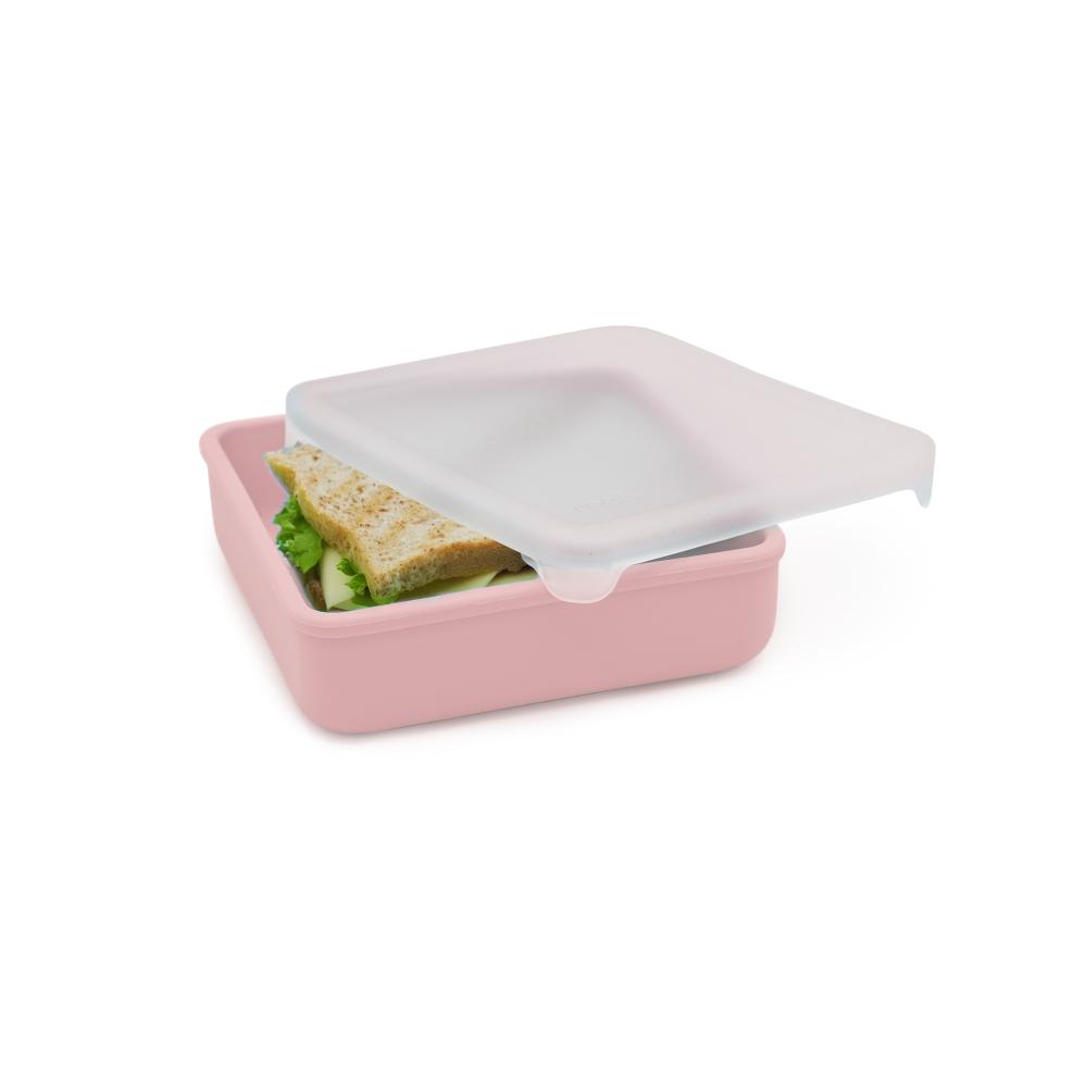 Pink lunch box with a sandwich and salad inside on a white background