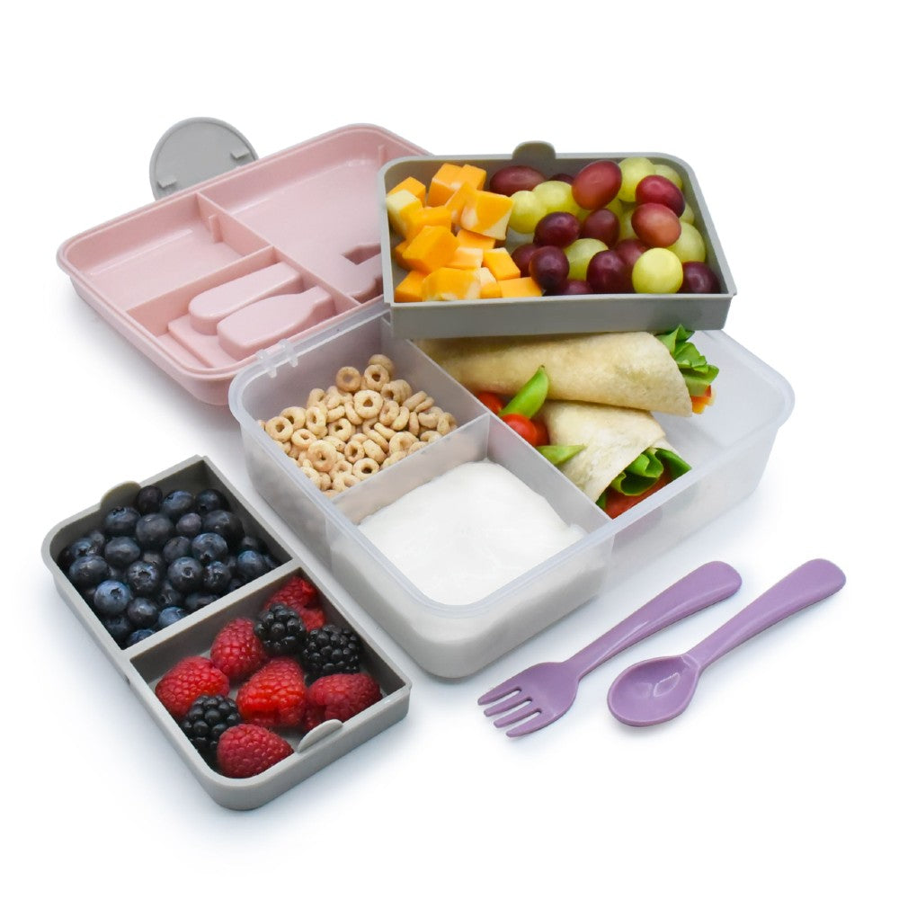 Bento box with compartments filled with food and a set of purple utensils on a white background