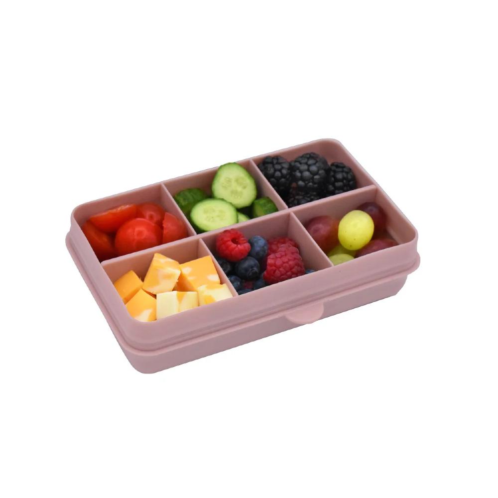 Pink compartmentalized snack box with fruits and vegetables on a white background