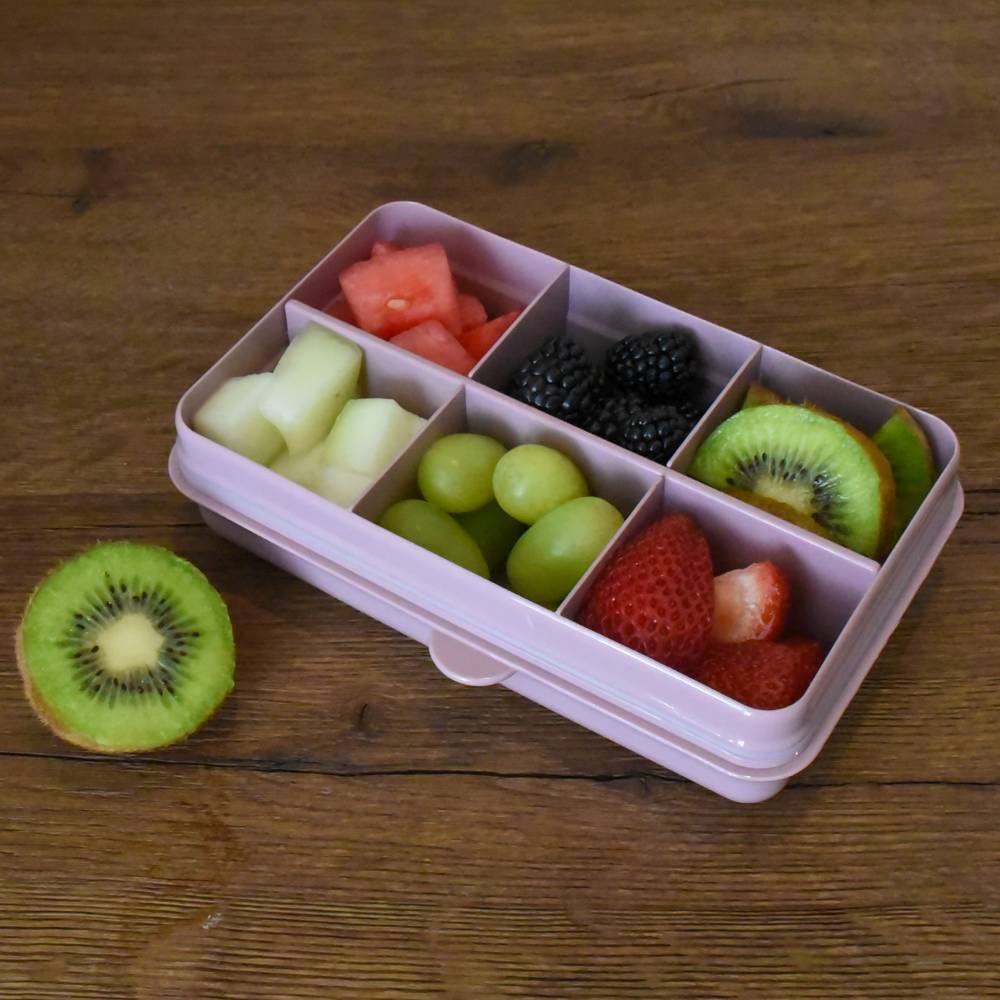 Fruit compartment container with compartments filled with various fruits on a wooden surface.