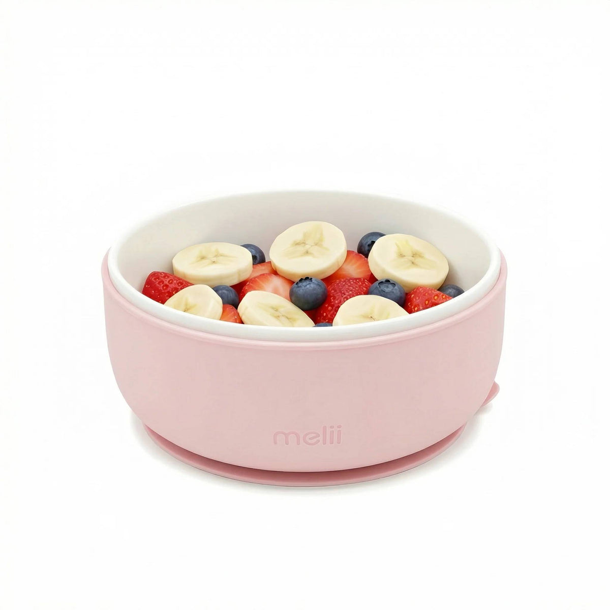 A ceramic bowl with a pink silicone sleeve, with strawberries, banana and blueberries, on a white background. 