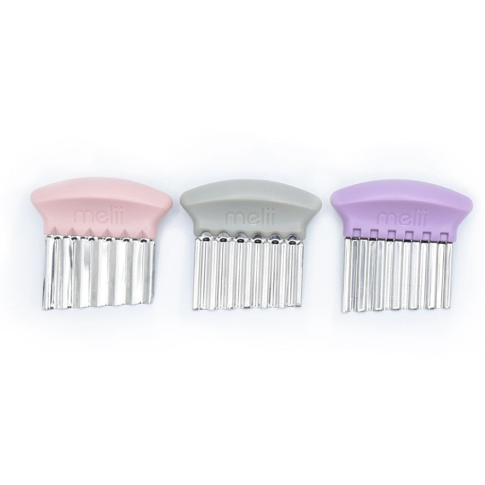 Three tools for cutting children's food in patterms with pink, gray, and purple handles on a white background