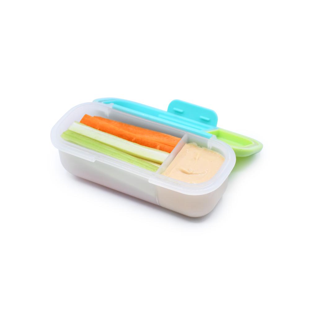 Container with compartments filled with vegetable sticks and dip on a white background