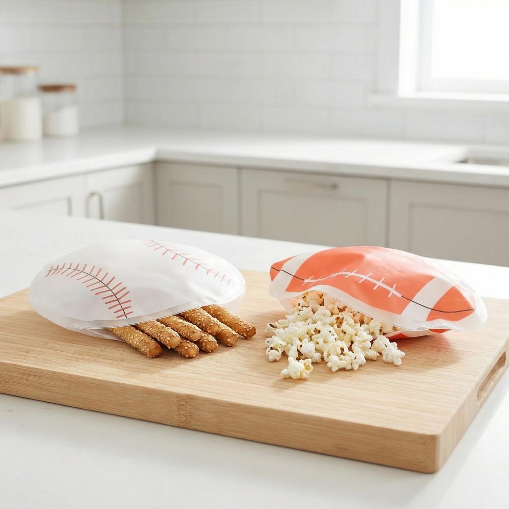 Wooden cutting board with baguettes, popcorn, and a football-themed bag on a kitchen counter.