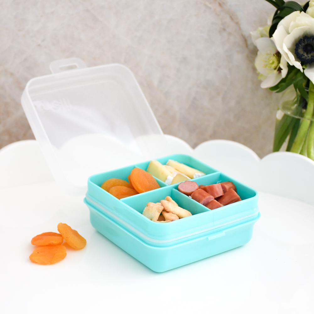 Blue bento box with compartments filled with snacks on a white surface.