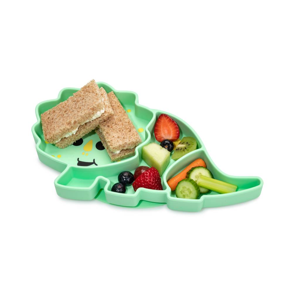 Green dinosaur-shaped silicone divided plate with snacks with yellow spots on a white background