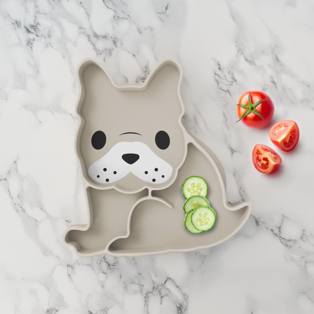 Dog-shaped plate with sliced cucumbers and tomatoes on a marble surface