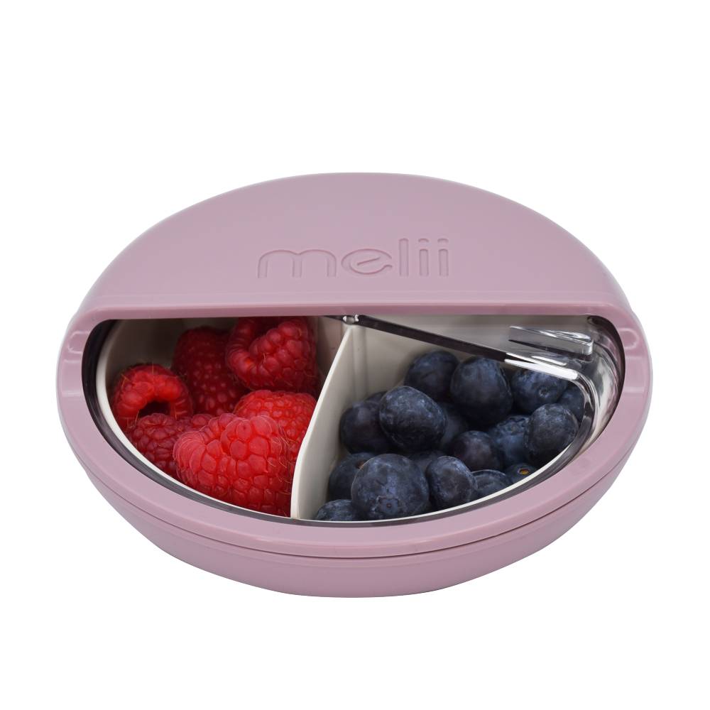 Pink round spin container with compartments filled with raspberries and blueberries on a white background