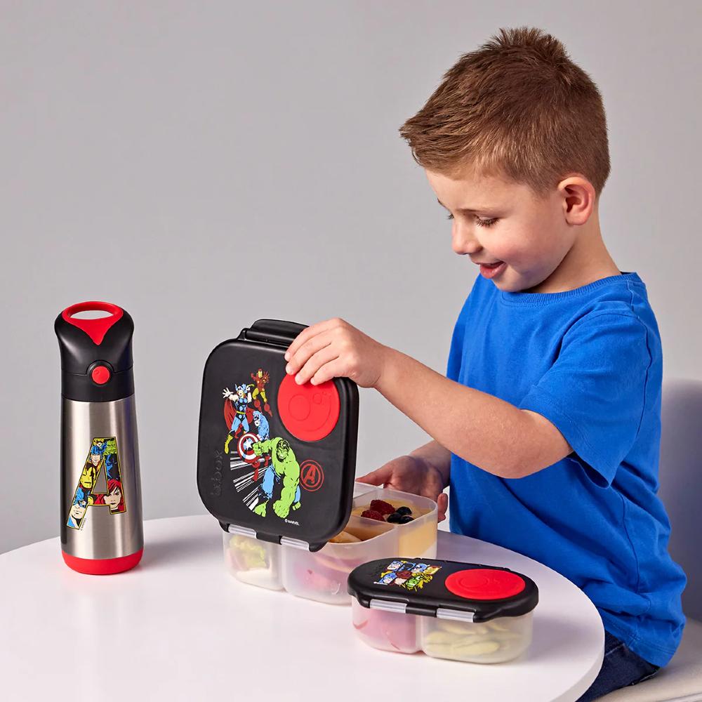 Child with superhero-themed lunch box and bottle on a gray background