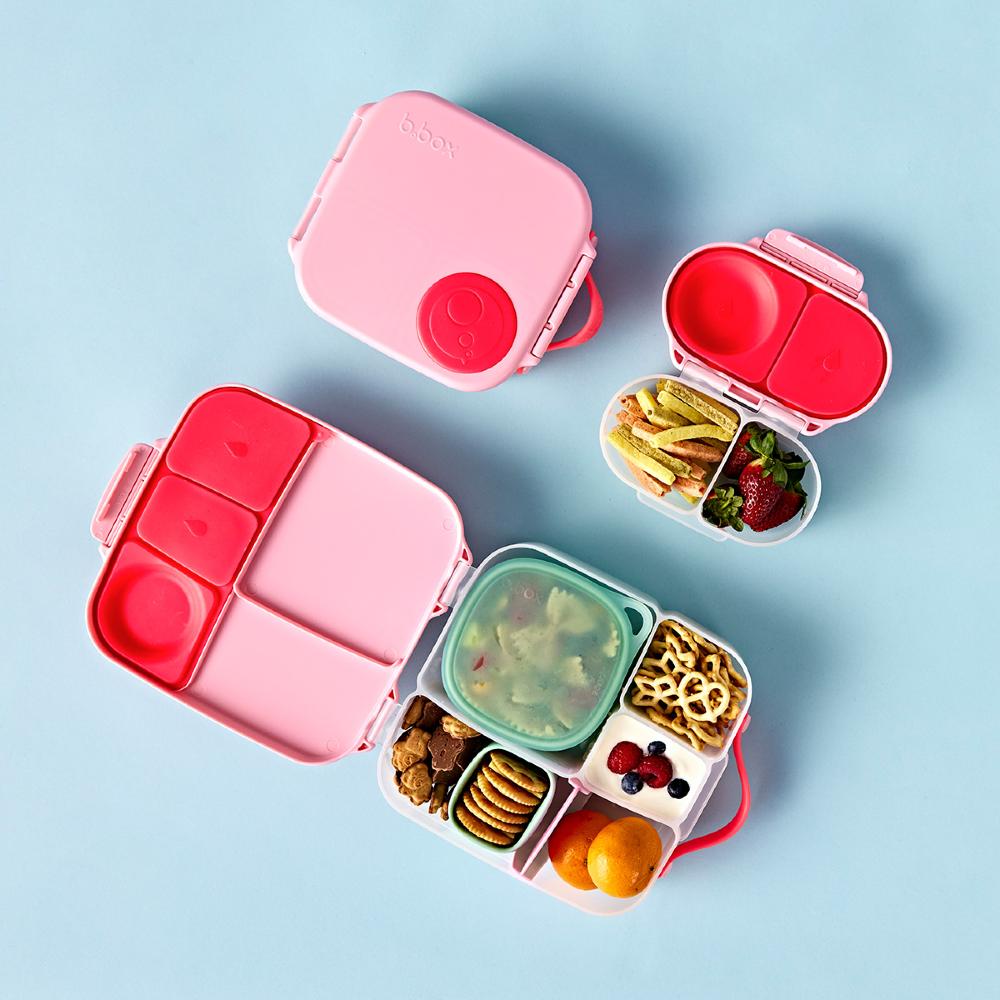 3 different sizes of a Pink and red bento box with compartments filled with snacks on a light blue background