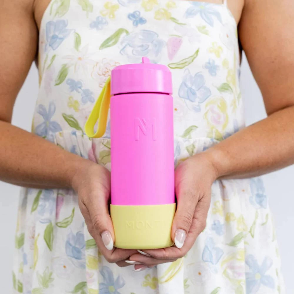 Pink stainless steel drink bottle with yellow bumper, held by a child