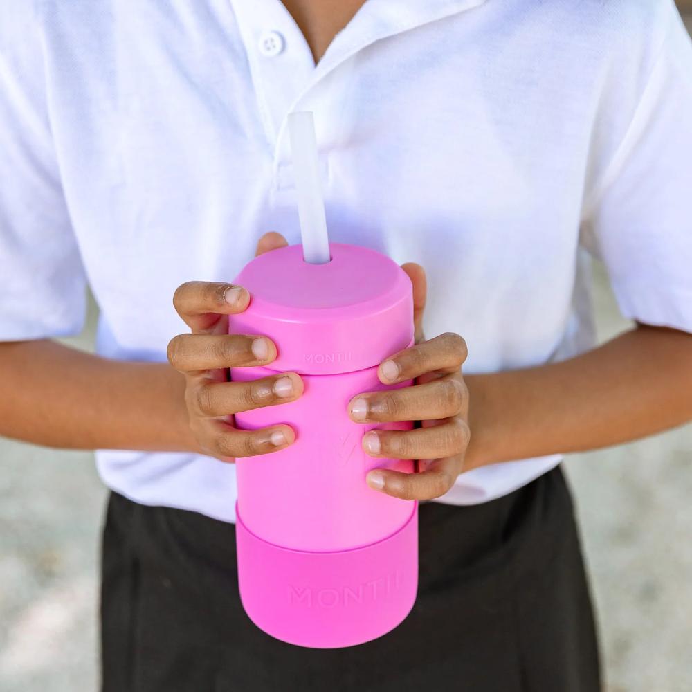 A child holding a calypso pink smoothie cup with a silicone straw. 