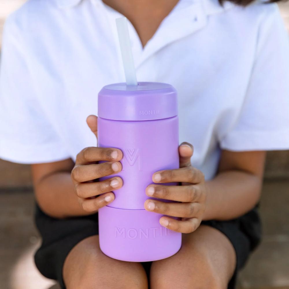 A child holding a dusk purple smoothie cup with a silicone straw. 