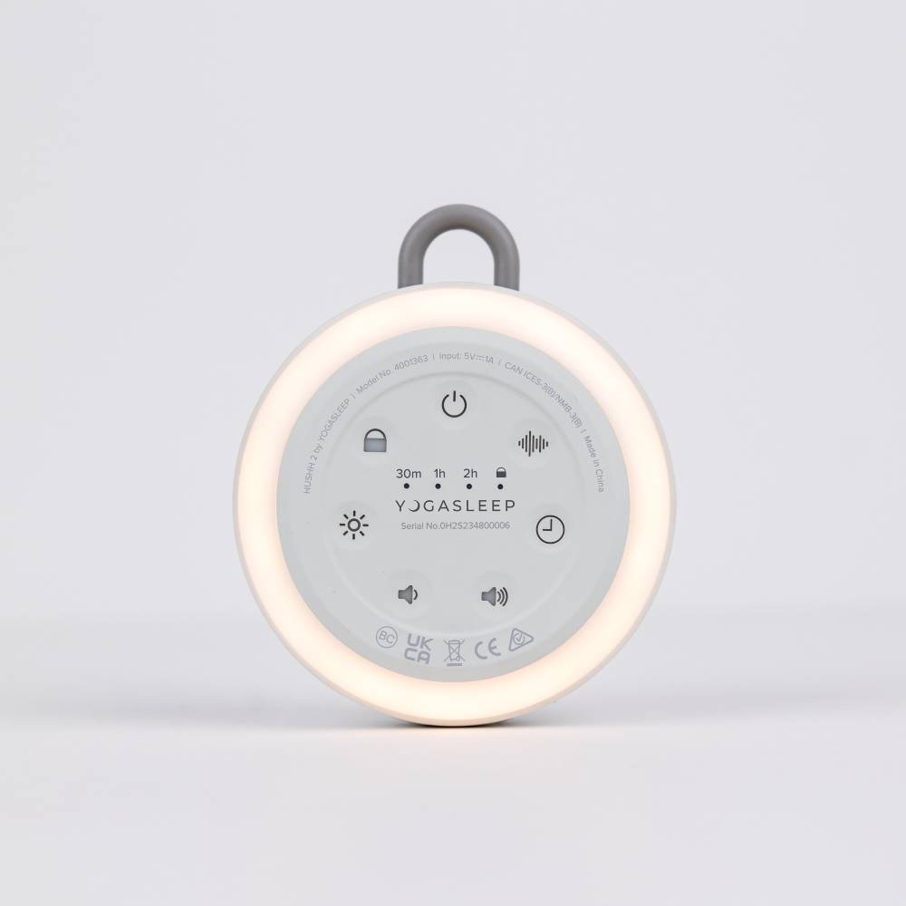Yogasleep baby soother with light on and control buttons visible on a light gray background