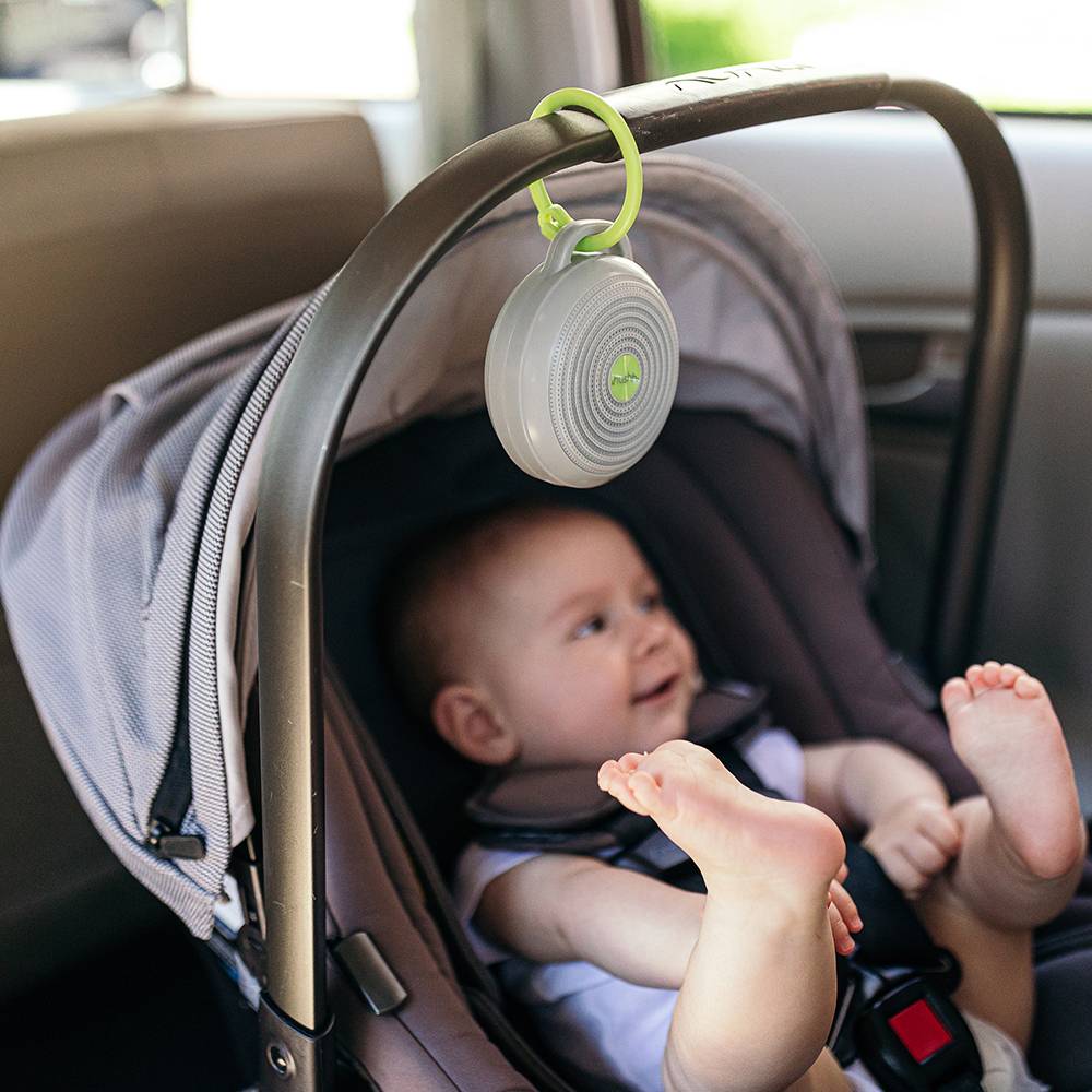 Baby in a carseat with a Yogasleep Hushh hanging on the handle. 