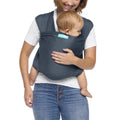 Mum carrying baby in blue Moby baby carrier against white background.