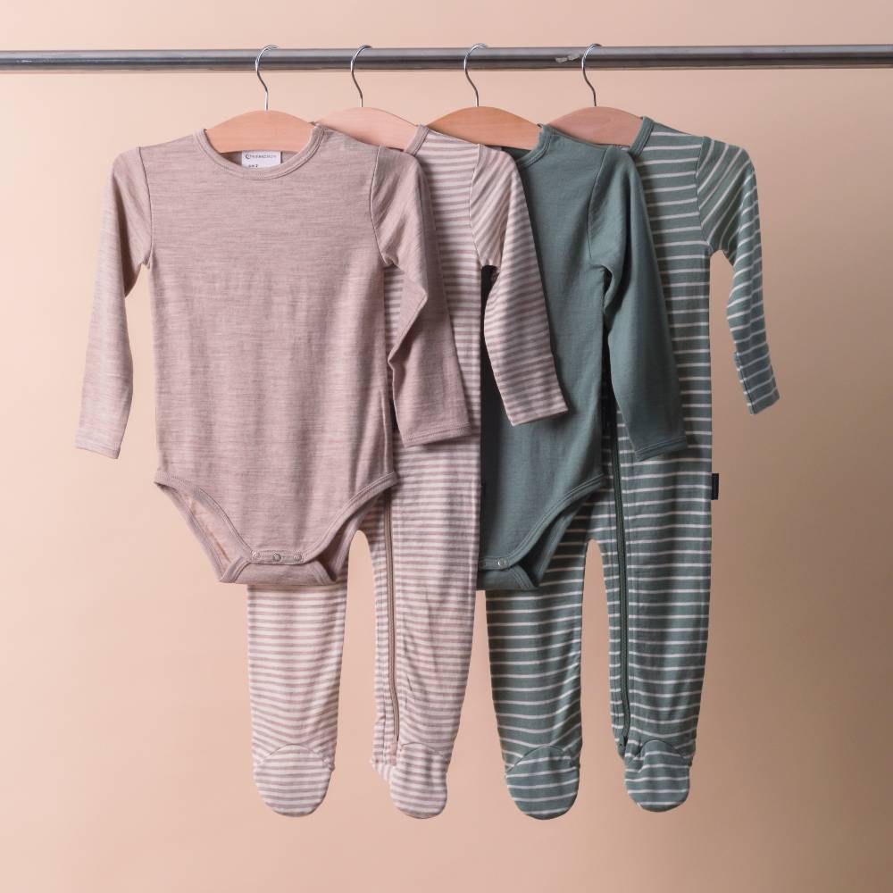 Two pairs of baby clothing on hangers against a beige background