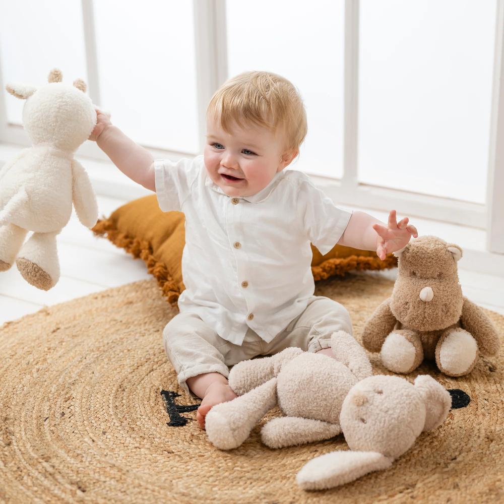 Baby playing with stuffed animals on a textured rug