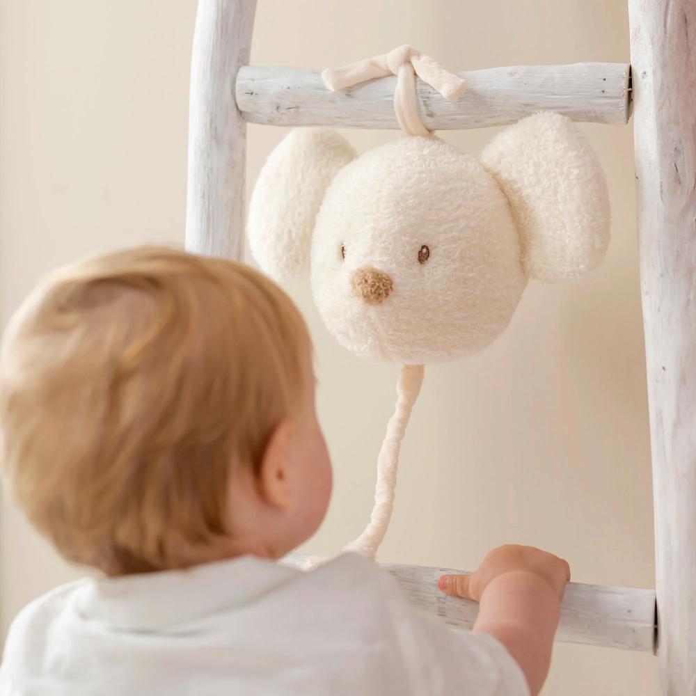 Baby looking at a plush toy hanging from a ladder in a nursery.